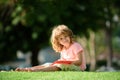 Preschool smiling pupil student boy writing to notebook in park on grass. Home children learning. Education childhood Royalty Free Stock Photo