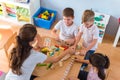 Preschool teacher with children playing with colorful didactic toys at kindergarten