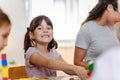 Preschool teacher with children playing with colorful wooden didactic toys at kindergarten