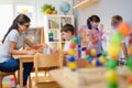 Preschool teacher with children playing with colorful wooden didactic toys at kindergarten Royalty Free Stock Photo