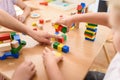 Preschool teacher with children playing with colorful wooden didactic toys at kindergarten