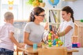 Preschool teacher with children playing with colorful didactic toys at kindergarten