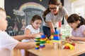 Preschool Teacher With Children Playing With Colorful Wooden Didactic Toys At Kindergarten