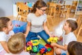 Preschool teacher talking to group of children sitting on a floor at kindergarten Royalty Free Stock Photo