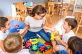 Preschool teacher talking to group of children sitting on a floor at kindergarten