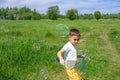 Preschooler boy blows big soap bubbles in a field on a bright sunny day Royalty Free Stock Photo