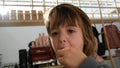 Preschooler boy eats lollipop standing in coatroom closeup