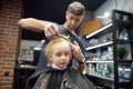 Preschooler boy getting haircut in barbershop. Children hairdresser with professional tools - comb and scissors. Cutting hair for Royalty Free Stock Photo