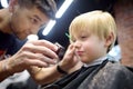 Preschooler boy getting haircut in barbershop. Children hairdresser with professional tools - comb and scissors. Cutting hair for Royalty Free Stock Photo