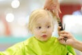 Preschooler boy getting haircut. Children hairdresser with professional tools - comb and scissors Royalty Free Stock Photo