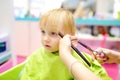 Preschooler boy getting haircut. Children hairdresser with professional tools - comb and scissors Royalty Free Stock Photo