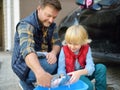 Preschooler boy helping his father washing family car. Little dad helper. Family with children spends time together Royalty Free Stock Photo