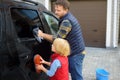 Preschooler boy helping his father washing family car. Little dad helper. Family with children spends time together Royalty Free Stock Photo