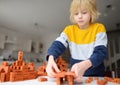 Preschooler boy is playing with real small clay bricks at the table at home. Child having fun and building smart constructions. Royalty Free Stock Photo
