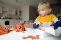 Preschooler boy is playing with real small clay bricks at the table at home. Child having fun and building smart constructions. Royalty Free Stock Photo