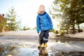 Preschooler boy is playing with a stick in brook on sunny spring day. Child having fun and enjoy a big puddle. All kids love play Royalty Free Stock Photo