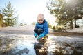Preschooler boy is playing with a stick in brook on sunny spring day. Child having fun and enjoy a big puddle. All kids love play Royalty Free Stock Photo