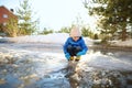 Preschooler boy is playing with a stick in brook on sunny spring day. Child having fun and enjoy a big puddle. All kids love play Royalty Free Stock Photo