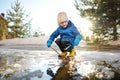 Preschooler boy is playing with a stick in brook on sunny spring day. Child having fun and enjoy a big puddle. All kids love play Royalty Free Stock Photo