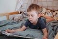 Preschooler boy reading book laying in his bed. spending time at home. Lifestyle family concept Royalty Free Stock Photo