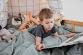 Preschooler boy reading book laying in his bed. spending time at home. Lifestyle family concept Royalty Free Stock Photo