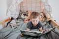 Preschooler boy reading book laying in his bed. spending time at home. Lifestyle family concept Royalty Free Stock Photo