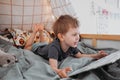 Preschooler boy reading book laying in his bed. spending time at home. Lifestyle family concept Royalty Free Stock Photo