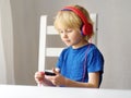 Preschooler child enjoy listen music or audiobook using his headphones at home