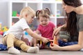 Preschooler children playing with educational wooden toys at kindergarten or day care center. Toddlers with teacher in