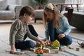 Preschooler children sit on floor playing at home together