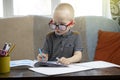 Preschooler is engaged in home schooling. The boy sits at a table, writes, draws and learns online on the Internet. Quarantine Royalty Free Stock Photo