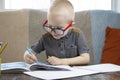 Preschooler is engaged in home schooling. The boy sits at a table, writes, draws and learns online on the Internet. Quarantine Royalty Free Stock Photo