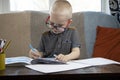 Preschooler is engaged in home schooling. The boy sits at a table, writes, draws and learns online on the Internet. Quarantine Royalty Free Stock Photo