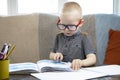 Preschooler is engaged in home schooling. The boy sits at a table, writes, draws and learns online on the Internet. Quarantine Royalty Free Stock Photo