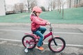 Preschooler girl riding pink bike bicycle in helmet on backyard road outside on spring autumn day Royalty Free Stock Photo