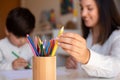 Preschooler kid drawing with coloured pencils with mother or teacher educator. Focus on the pencils. Homeschooling. Learning