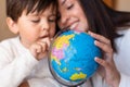 Preschooler Kid learing geography with a globe map and teacher educador help. Homeshooling. Learning Community. Montessori School