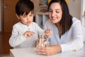 Preschooler Kid playing with wood 3d puzzle and teacher educador help. Homeshooling. Learning Community. Montessori School