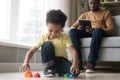 Preschooler son playing with toys while African American father working Royalty Free Stock Photo