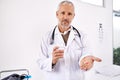 Prescribing you the best medicine. Portrait of a mature male doctor holding a glass of water and medicine in his hand. Royalty Free Stock Photo