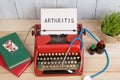 Prescription medicine or medical diagnosis - doctor workplace with stethoscope, pills, typewriter with text Arthritis