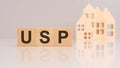 acronym USP stands for 'Unique Selling Proposition' on wooden cubes with models house on background. Royalty Free Stock Photo