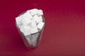 The presence of a huge amount of sugar in a glass of soda. Top view. Sugar cubes jn the glass on red background. Royalty Free Stock Photo