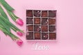 Box with chocolate sweets and tulips on pink background. Desert for Valentine Day Royalty Free Stock Photo