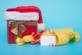 Present box covered by santa claus hat and wrapped wine with blank card for text on blue Royalty Free Stock Photo