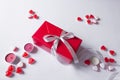 Present box in red paper with silver ribbon bow. White background with jelly hearts and candles. Holidays sale concept. Royalty Free Stock Photo