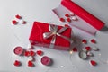 Present box wrapped in red paper with silver ribbon bow. White background with jelly hearts, candles and paper roll. Royalty Free Stock Photo