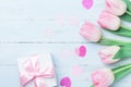 Present or gift box and pink flowers on blue wooden table top view. Greeting card for Womans or Mothers Day. Flat lay. Royalty Free Stock Photo