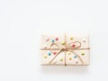 A present or gift box wrapped by rough brown recycled paper and tied with brown hemp rope as ribbon with multi color star isolated Royalty Free Stock Photo