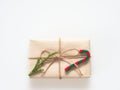 A present or gift box wrapped by rough brown recycled paper and tied with brown hemp rope ribbon with pine branch and candy cane i Royalty Free Stock Photo